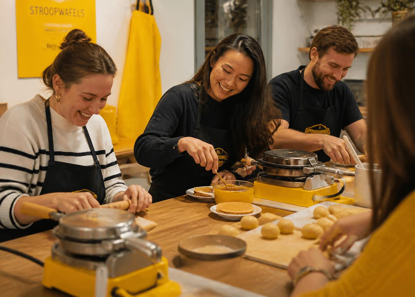 Deelnemers bakken samen stroopwafels tijdens een workshop